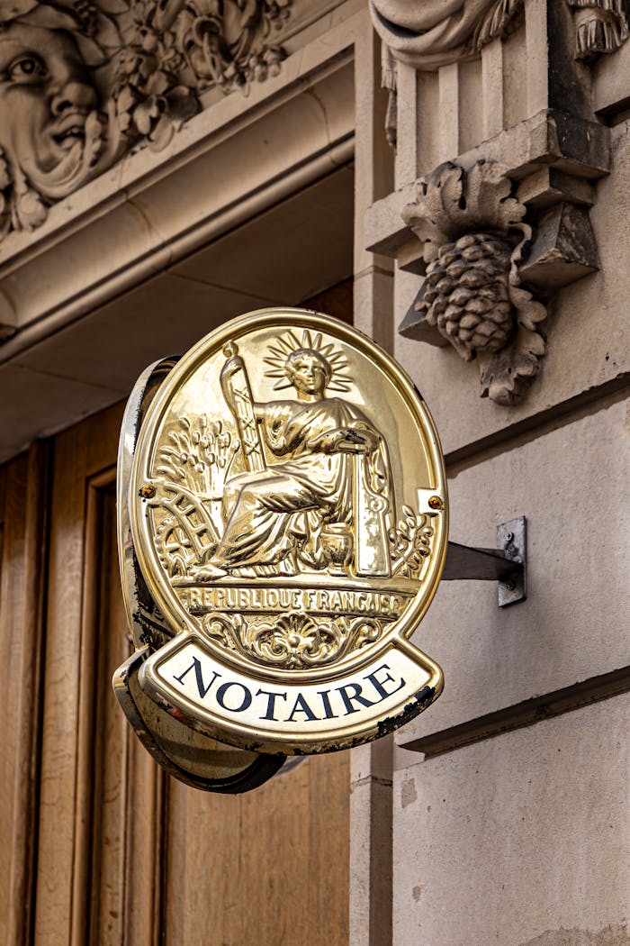 home-img Classic notary sign on a historic Parisian building facade in daylight.